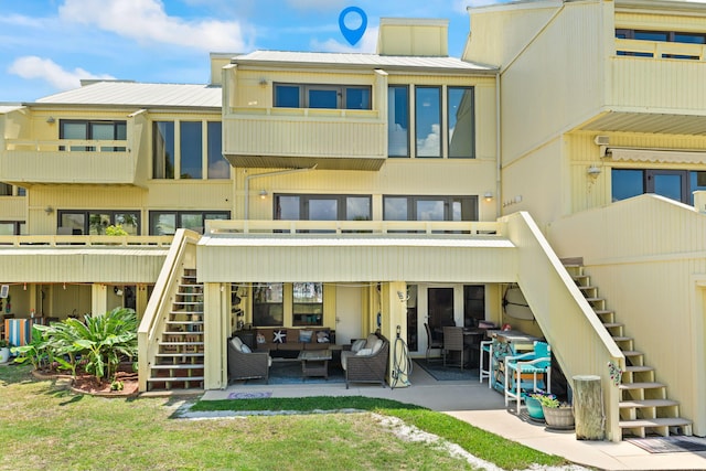 back of house with stairs, metal roof, an outdoor hangout area, and a patio