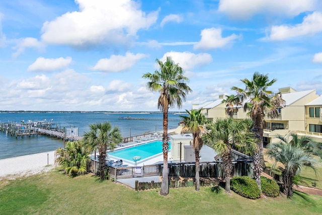 view of swimming pool featuring a lawn, a water view, and fence