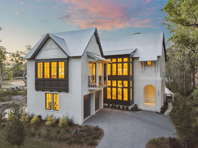 335 Churchill Oaks Dr, Santa Rosa Beach, FL 32459 - view of front of home with a garage, a balcony, driveway, brick siding, and metal roof