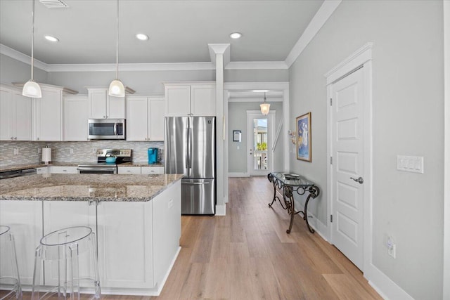 1454 Seaside Cir, Navarre, FL 32566 - kitchen with appliances with stainless steel finishes, light stone counters, white cabinetry, decorative backsplash, and light wood-type flooring