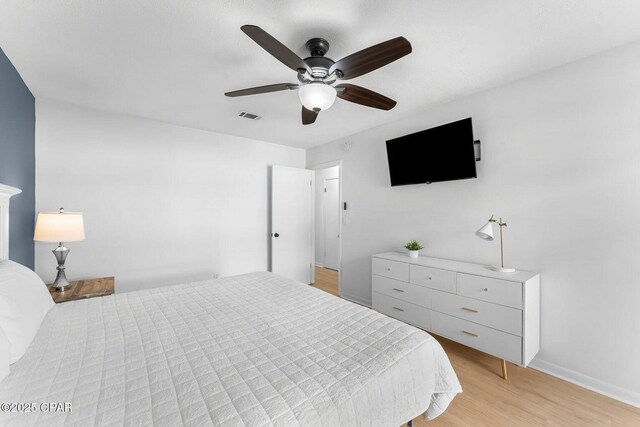 bedroom with light wood finished floors, visible vents, baseboards, and ceiling fan
