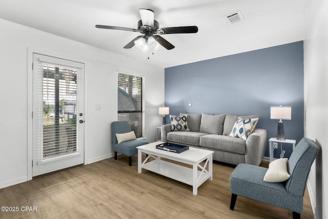 living area with light wood-style floors, ceiling fan, baseboards, and visible vents