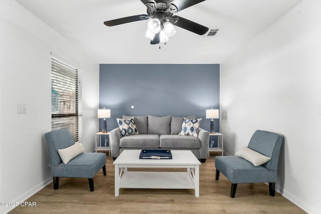 living room featuring wood finished floors, baseboards, a ceiling fan, and visible vents