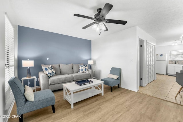 living room with light wood-style flooring, ceiling fan, and baseboards
