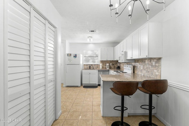 kitchen with tasteful backsplash, visible vents, white cabinets, white appliances, and a peninsula