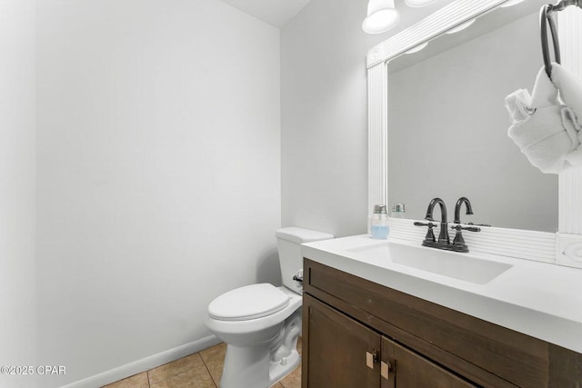 half bathroom with tile patterned floors, vanity, baseboards, and toilet