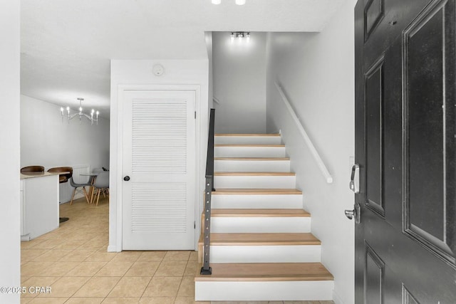 staircase with tile patterned floors and a notable chandelier