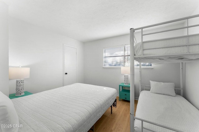 bedroom with a textured ceiling and wood finished floors