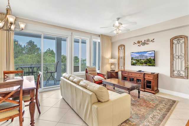 living room with ceiling fan with notable chandelier, light tile patterned floors, and baseboards