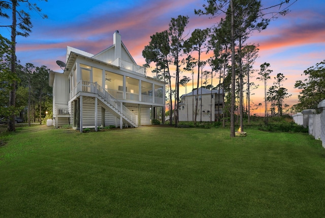 205 Mallard Ln, Santa Rosa Beach, FL 32459 - back of house at dusk featuring a lawn, a ceiling fan, a sunroom, and stairs