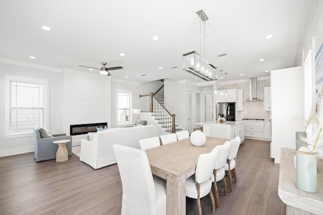 dining area with recessed lighting, a large fireplace, stairway, ornamental molding, and wood finished floors