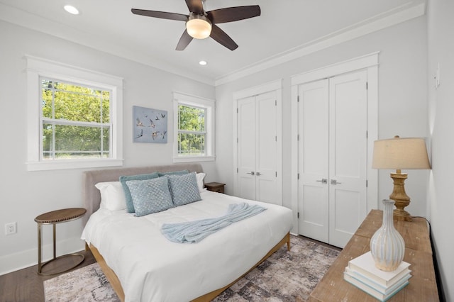 bedroom featuring recessed lighting, two closets, ceiling fan, baseboards, and wood finished floors