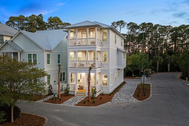 view of property with metal roof, a porch, and a balcony