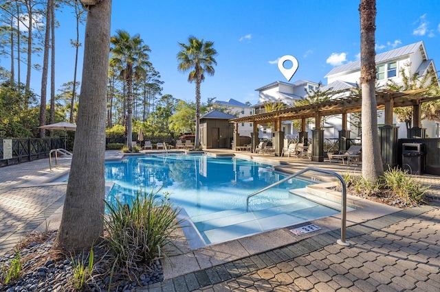 community pool featuring fence, an outbuilding, a patio, a shed, and a pergola