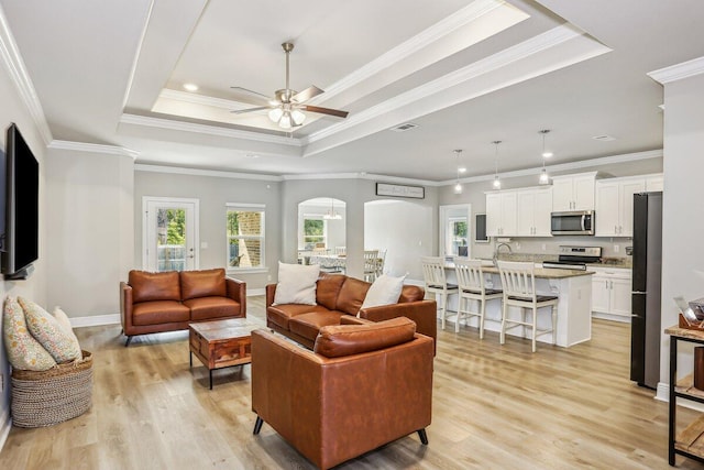 3291 Secret Isle Way, Navarre, FL 32566 - living room with arched walkways, a raised ceiling, plenty of natural light, a ceiling fan, and ornamental molding