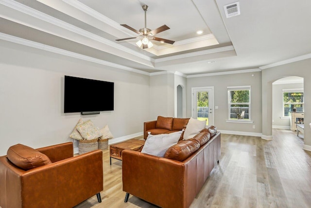 3291 Secret Isle Way, Navarre, FL 32566 - living room featuring arched walkways, a tray ceiling, light wood finished floors, a ceiling fan, and ornamental molding