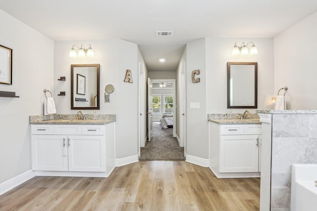3291 Secret Isle Way, Navarre, FL 32566 - bathroom with wood finished floors, baseboards, a bath, and two vanities