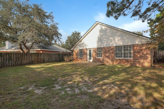 back of property with brick siding, a patio area, a lawn, and a fenced backyard