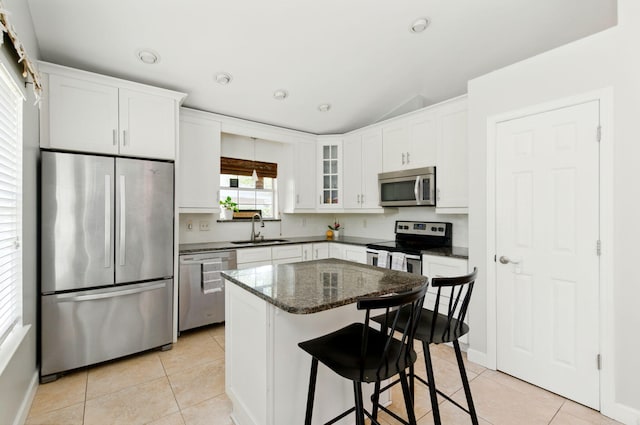 kitchen with light tile patterned flooring, vaulted ceiling, stainless steel appliances, and a sink
