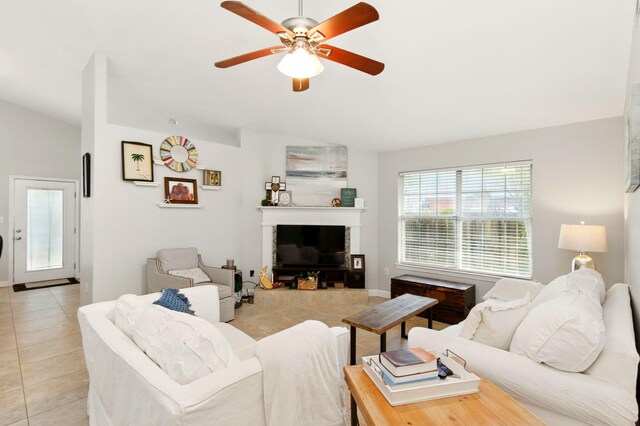 living room with vaulted ceiling, a ceiling fan, light tile patterned floors, baseboards, and a glass covered fireplace