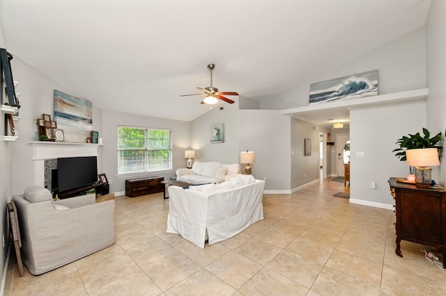 living area featuring a tile fireplace, vaulted ceiling, light tile patterned floors, baseboards, and ceiling fan