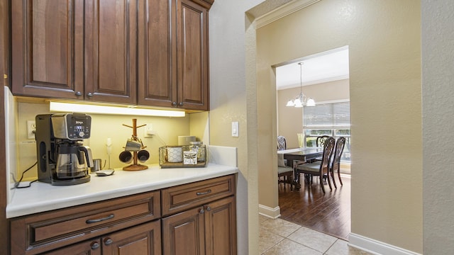 554 Magnolia Lake Dr, Defuniak Springs, FL 32433 - bar with a chandelier, light tile patterned floors, baseboards, decorative light fixtures, and a textured wall