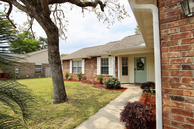 206 Secretariat Dr, Crestview, FL 32539 - view of exterior entry with brick siding, roof with shingles, and a yard