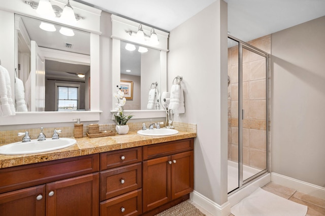 bathroom featuring a shower stall, double vanity, tile patterned flooring, and baseboards