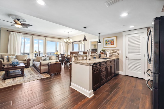 kitchen featuring appliances with stainless steel finishes, crown molding, a peninsula, a sink, and light stone countertops