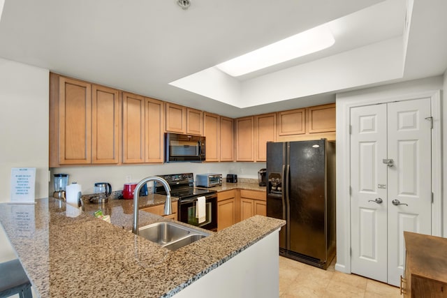 4203 Indian Bayou Trl Unit 1716, Destin, FL 32541 - kitchen featuring a sink, a peninsula, a tray ceiling, black appliances, and light stone counters