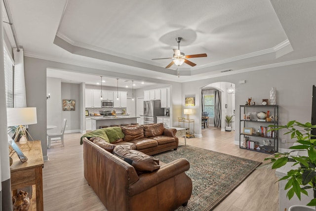 7045 Leisure St, Navarre, FL 32566 - living area with a tray ceiling, arched walkways, ceiling fan, light wood-type flooring, and baseboards