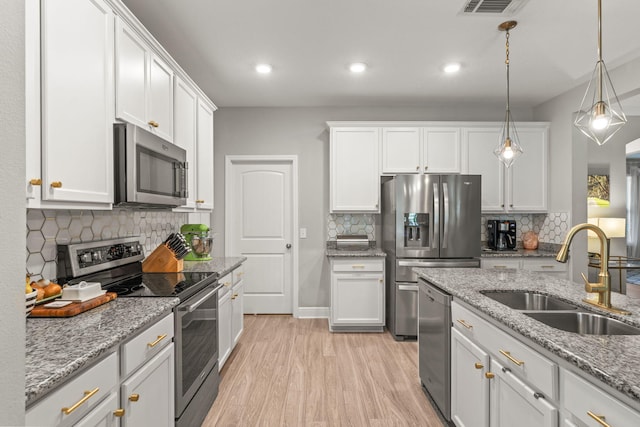 7045 Leisure St, Navarre, FL 32566 - kitchen featuring appliances with stainless steel finishes, a sink, light wood-type flooring, white cabinetry, and recessed lighting