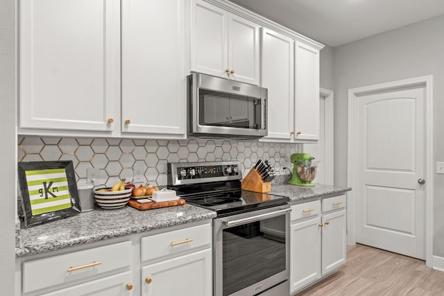 7045 Leisure St, Navarre, FL 32566 - kitchen with appliances with stainless steel finishes, light wood-style flooring, white cabinetry, tasteful backsplash, and light stone countertops