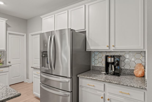 7045 Leisure St, Navarre, FL 32566 - kitchen with stainless steel refrigerator with ice dispenser, white cabinetry, decorative backsplash, light wood-type flooring, and light stone countertops