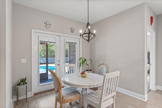 7045 Leisure St, Navarre, FL 32566 - dining space with french doors, light wood finished floors, baseboards, and a chandelier