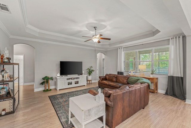 7045 Leisure St, Navarre, FL 32566 - living room with arched walkways, a raised ceiling, a ceiling fan, light wood finished floors, and ornamental molding