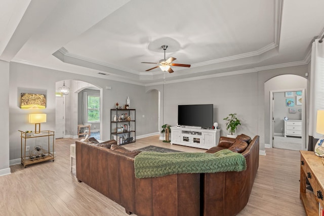 7045 Leisure St, Navarre, FL 32566 - living area with arched walkways, a tray ceiling, light wood-style flooring, a ceiling fan, and ornamental molding