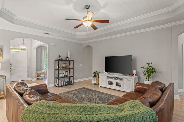 7045 Leisure St, Navarre, FL 32566 - living area featuring arched walkways, light wood-style floors, a ceiling fan, a raised ceiling, and crown molding