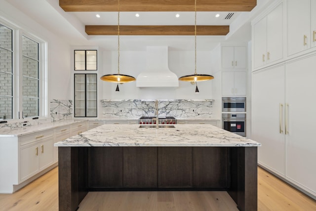 724 Windsong Dr, Inlet Beach, FL 32461 - kitchen with backsplash, premium range hood, light wood-style floors, beamed ceiling, and white cabinetry