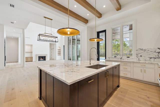 724 Windsong Dr, Inlet Beach, FL 32461 - kitchen with beamed ceiling, light wood-style floors, a center island with sink, and a sink
