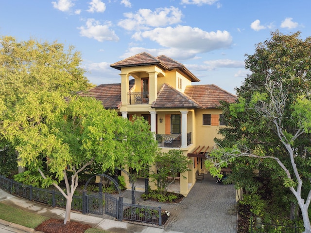 30 Place De La Fontaine, Miramar Beach, FL 32550 - mediterranean / spanish house featuring a fenced front yard, a balcony, driveway, a tiled roof, and stucco siding