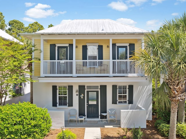 view of front facade with metal roof, a standing seam roof, covered porch, and a balcony