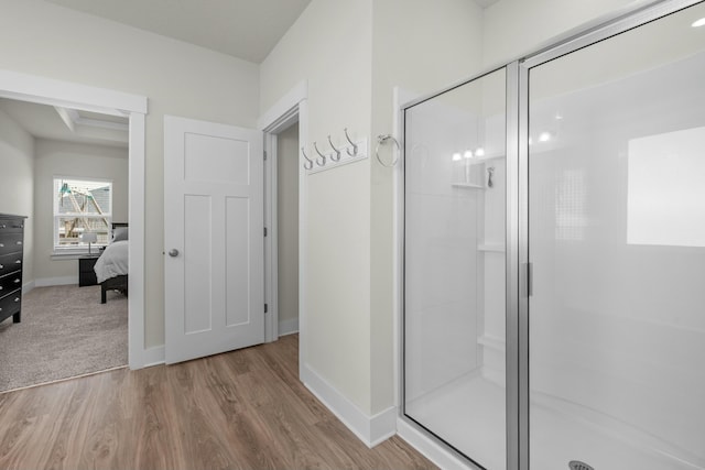 bathroom with a stall shower, wood finished floors, baseboards, and ensuite bath