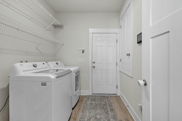laundry room with washer and clothes dryer, light wood-style floors, and baseboards