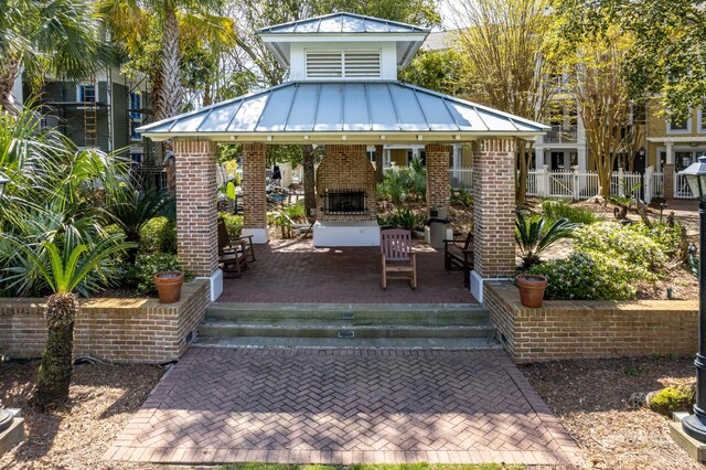 9200 Baytowne Wharf Blvd Unit 441, Miramar Beach, FL 32550 - back of house featuring an outdoor brick fireplace, a gazebo, a standing seam roof, brick siding, and fence