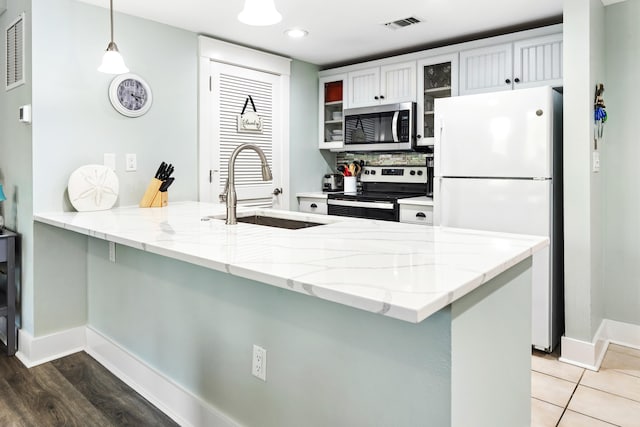 9200 Baytowne Wharf Blvd Unit 441, Miramar Beach, FL 32550 - kitchen featuring stainless steel appliances, a sink, a peninsula, pendant lighting, and glass insert cabinets