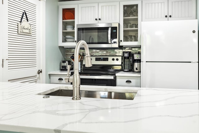 9200 Baytowne Wharf Blvd Unit 441, Miramar Beach, FL 32550 - kitchen featuring freestanding refrigerator, stainless steel microwave, backsplash, and light stone counters
