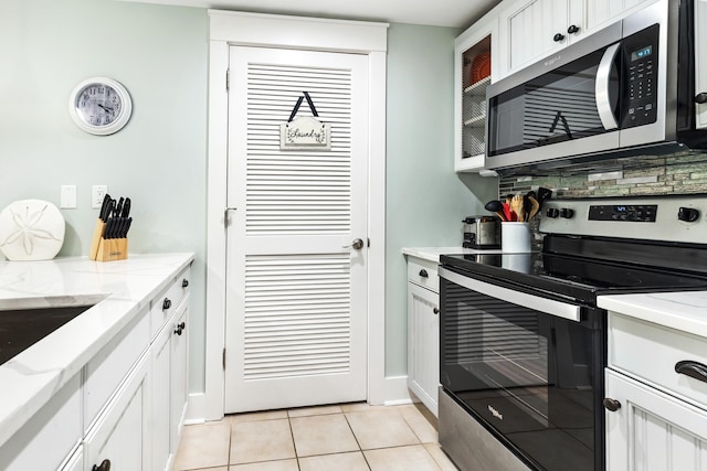 9200 Baytowne Wharf Blvd Unit 441, Miramar Beach, FL 32550 - kitchen with stainless steel appliances, light tile patterned flooring, white cabinets, glass insert cabinets, and light stone counters
