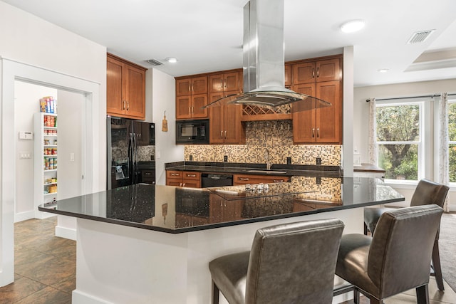 135 Bayou Point Dr, Santa Rosa Beach, FL 32459 - kitchen featuring tasteful backsplash, visible vents, island range hood, black appliances, and a breakfast bar area