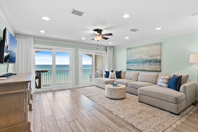 living area featuring ceiling fan, wood finished floors, visible vents, and ornamental molding